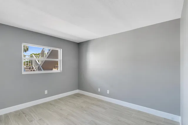 a view of an empty room with wooden floor and window