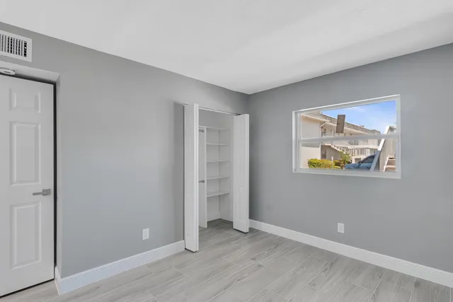 a view of an empty room with wooden floor and closet
