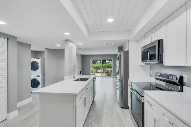 a kitchen with a sink a stove top oven a refrigerator cabinets and a dining table