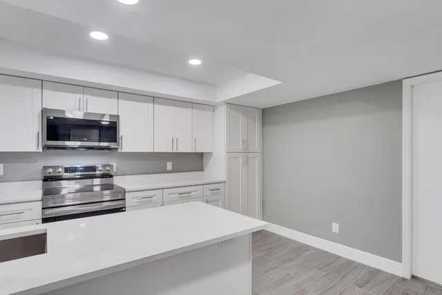 a kitchen with stainless steel appliances a microwave a stove and white cabinets