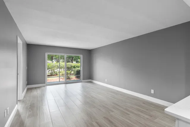 a view of an empty room with wooden floor and a window