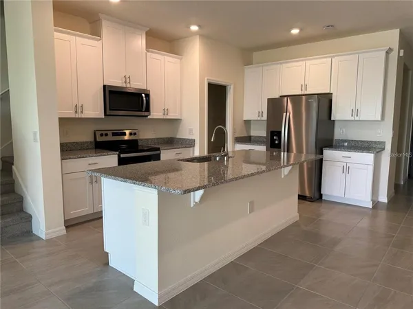 a kitchen with stainless steel appliances granite countertop a refrigerator oven a sink a stove and a microwave