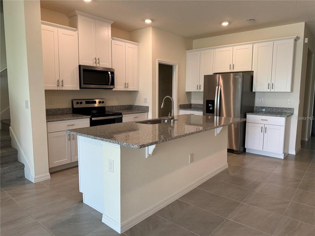 4561 Small Creek Road Kissimmee, FL 34744 - Photo 4 of 32 a kitchen with stainless steel appliances granite countertop a refrigerator oven a sink a stove and a microwave