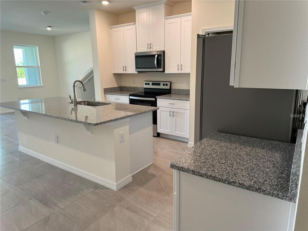 4561 Small Creek Road Kissimmee, FL 34744 - Photo 6 of 32 a kitchen with stainless steel appliances granite countertop a sink stove and refrigerator