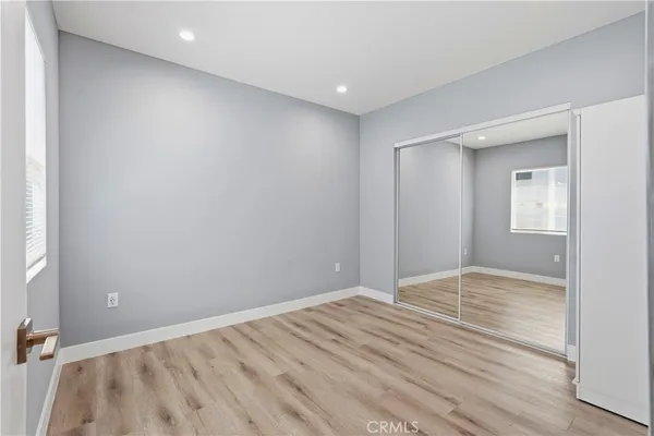 a view of an empty room with wooden floor and closet