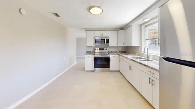 a kitchen with granite countertop a sink cabinets stainless steel appliances and a window