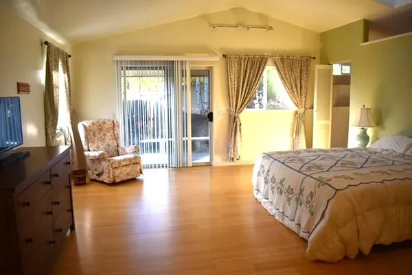 a spacious bedroom with a bed and wooden floor