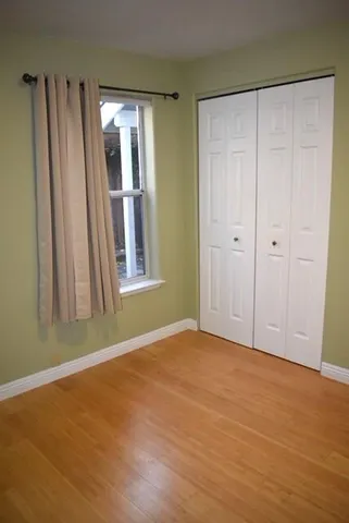 a view of an empty room with window and wooden floor