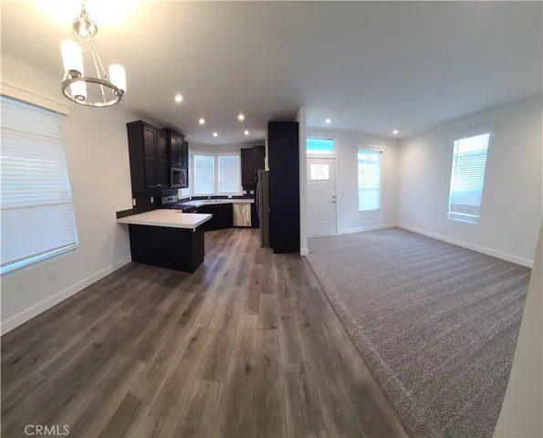 a living room with kitchen island granite countertop wooden floor stainless steel appliances and kitchen view