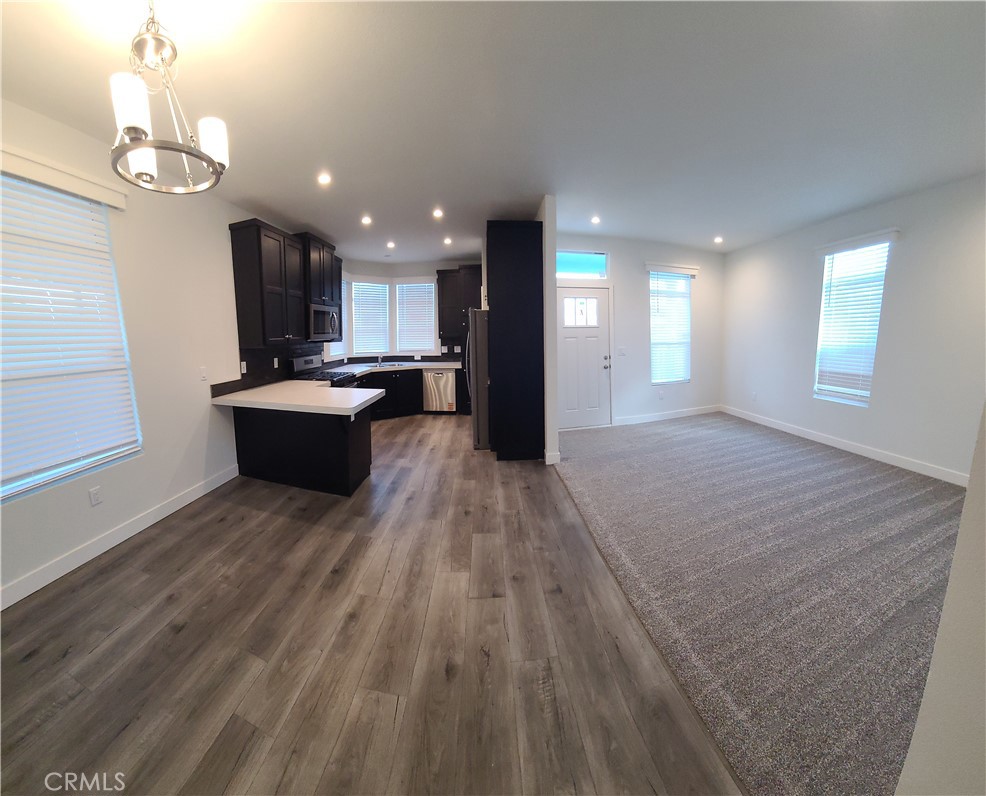 2139 East 4th Street, Unit 79 Ontario, CA 91764 - Photo 6 of 18 a living room with kitchen island granite countertop wooden floor stainless steel appliances and kitchen view