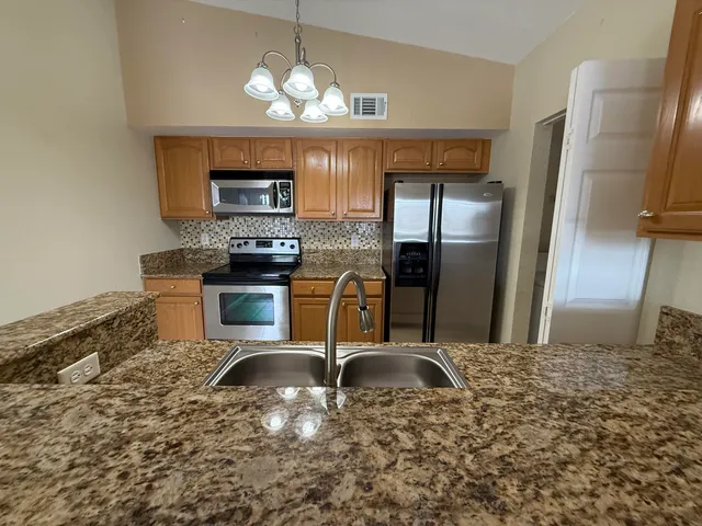 a kitchen with stainless steel appliances granite countertop a sink refrigerator stove and microwave