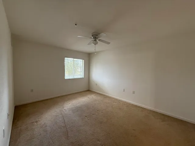 an empty room with a window and a ceiling fan