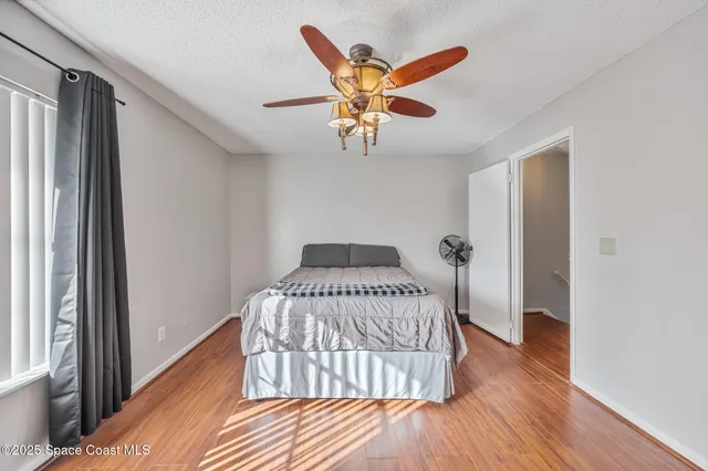 a view of a bedroom with wooden floor and a ceiling fan
