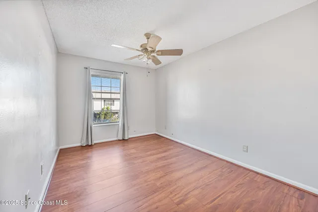 an empty room with wooden floor fan and windows
