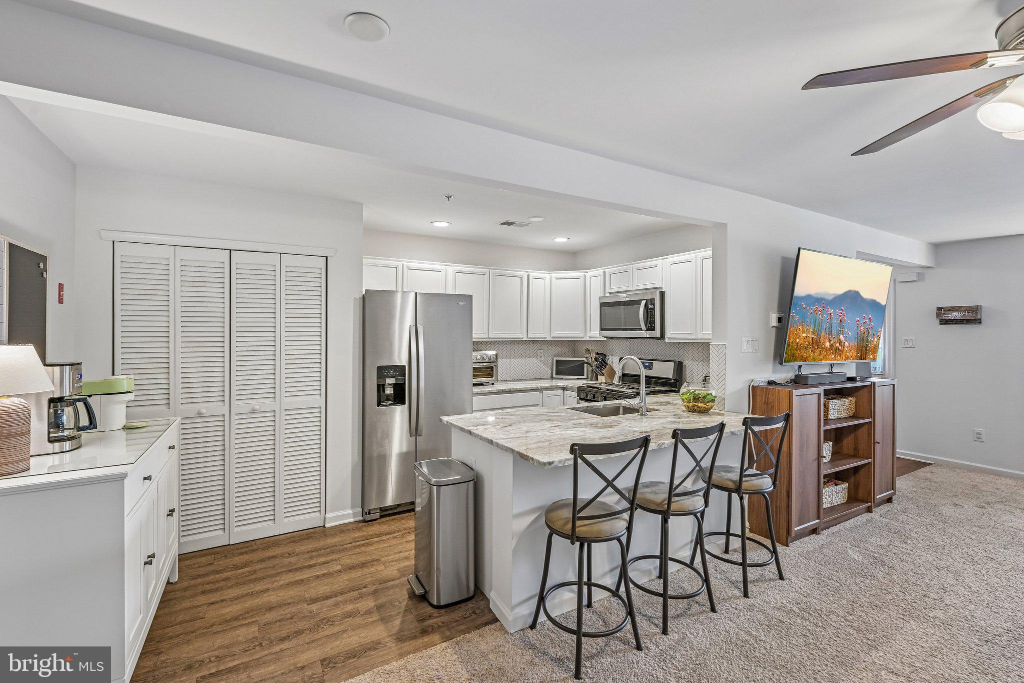 203 Flagstone Road, Unit 6 Chester Springs, PA 19425 - Photo 7 of 17 a kitchen with stainless steel appliances kitchen island granite countertop a refrigerator a stove a sink dishwasher and a dining table with wooden floor