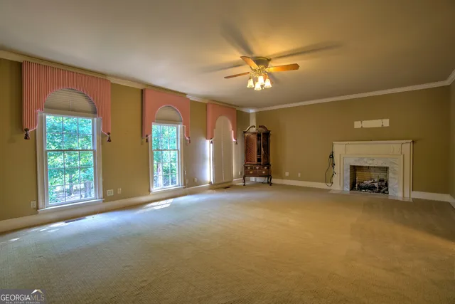 a view of an empty room with window and chandelier fan