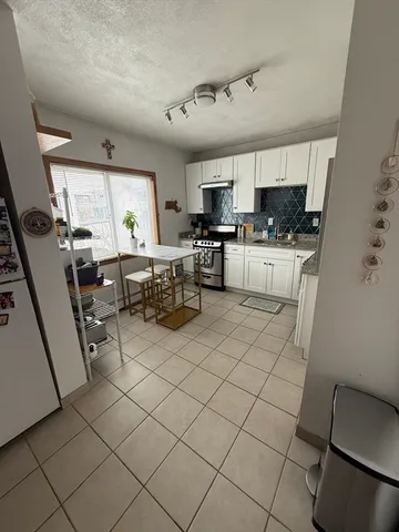 a living room with stainless steel appliances furniture a rug and a window