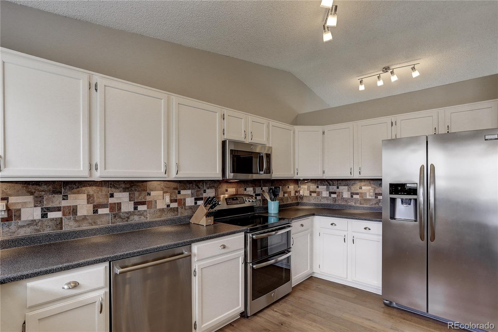 10626 Hyacinth Court Highlands Ranch, CO 80129 - Photo 11 of 38 a kitchen with stainless steel appliances granite countertop a refrigerator a sink a stove and white cabinets