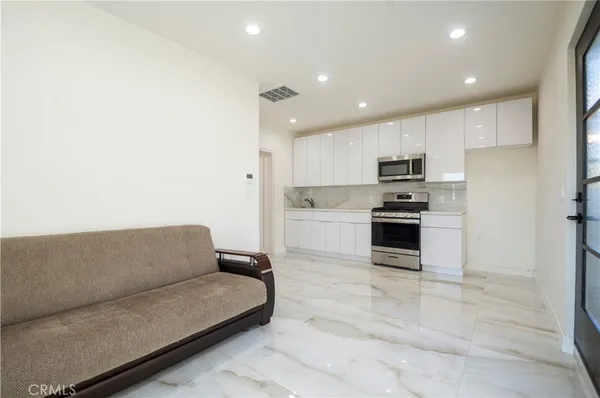 a living room with stainless steel appliances kitchen island granite countertop a couch and a sink