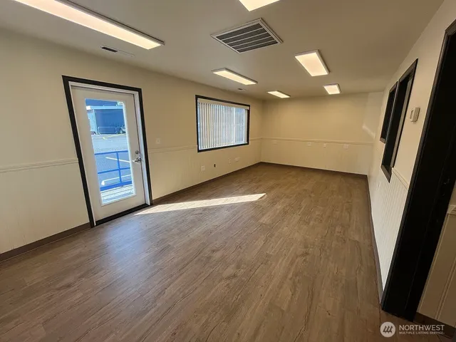 a view of an empty room with wooden floor and a window
