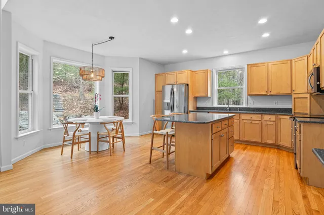 a kitchen with stainless steel appliances granite countertop a stove top oven a sink a dining table and chairs