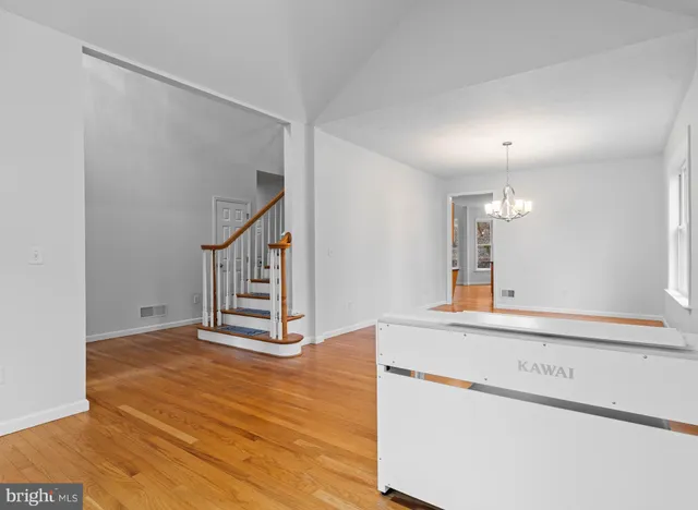 a view of an empty room with wooden floor and stairs