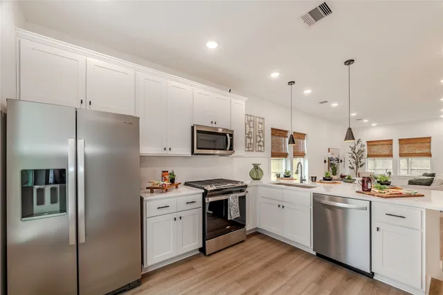 a kitchen with white cabinets and stainless steel appliances