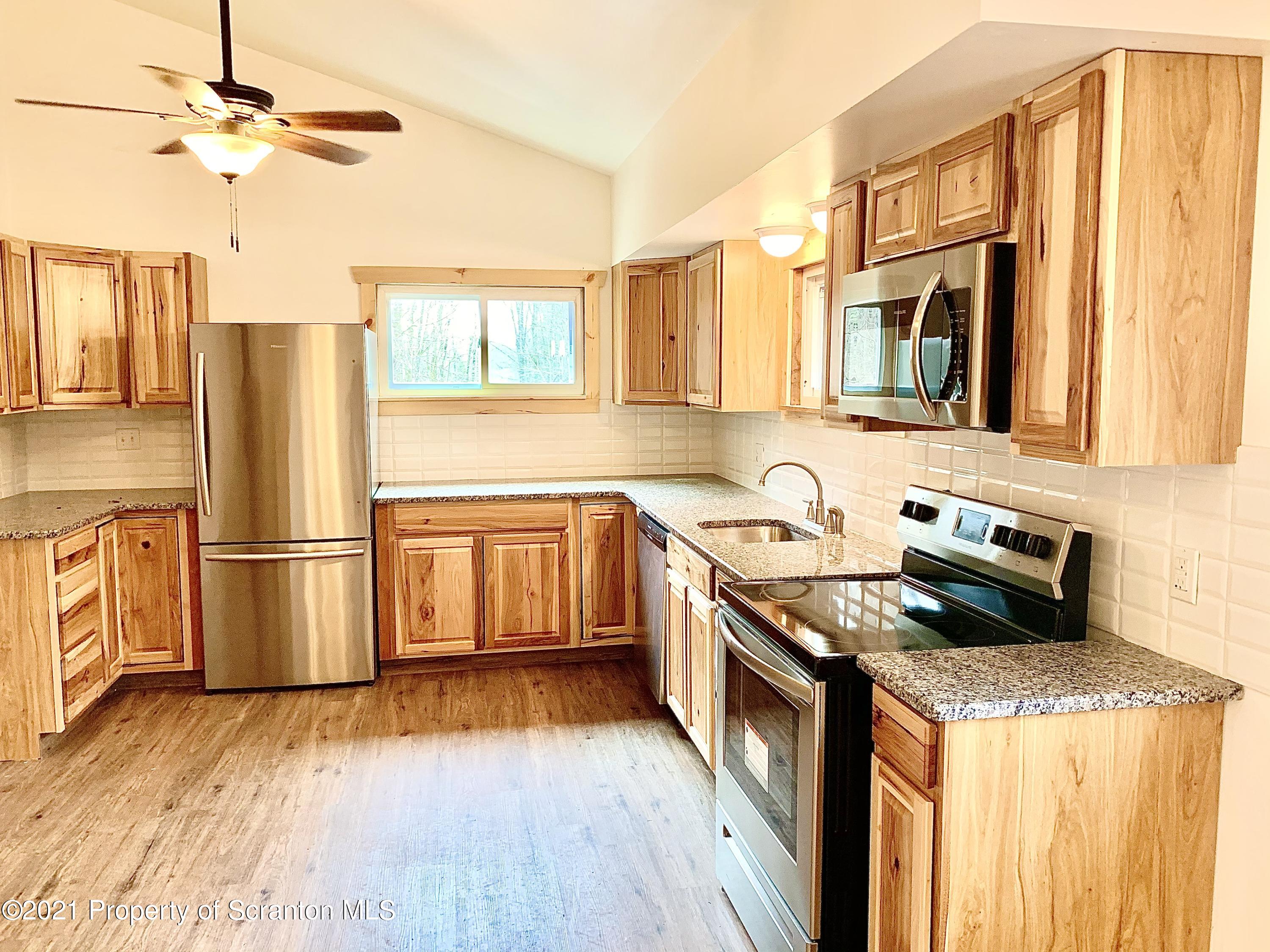 3886 Button Road Hop Bottom, PA 18824 - Photo 3 of 29 a kitchen with stainless steel appliances granite countertop a refrigerator a sink dishwasher a stove and white countertops with wooden floor
