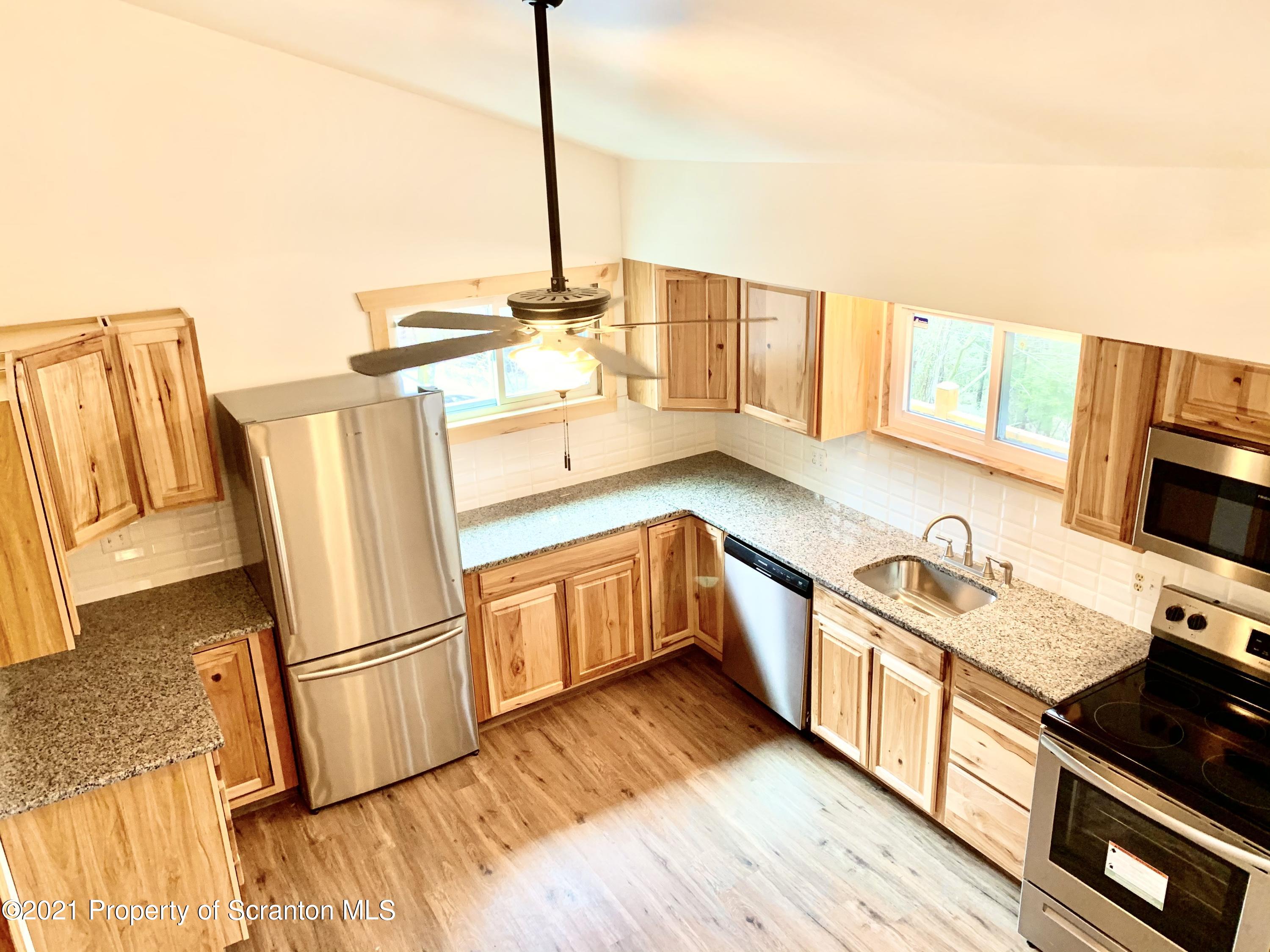 3886 Button Road Hop Bottom, PA 18824 - Photo 7 of 29 a kitchen with stainless steel appliances a stove top oven a sink a refrigerator and wooden floor