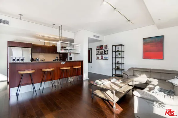 a living room with stainless steel appliances kitchen island granite countertop furniture and a wooden floor