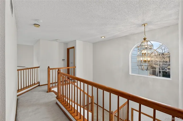 an empty room with a chandelier fan and windows
