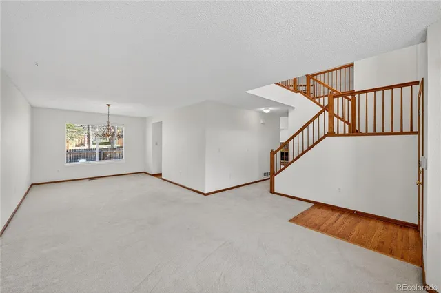 a view of an empty room with stairs and a window