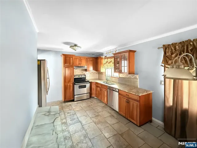 a kitchen with stainless steel appliances granite countertop a stove a sink and a granite counter tops with white cabinets next to a window