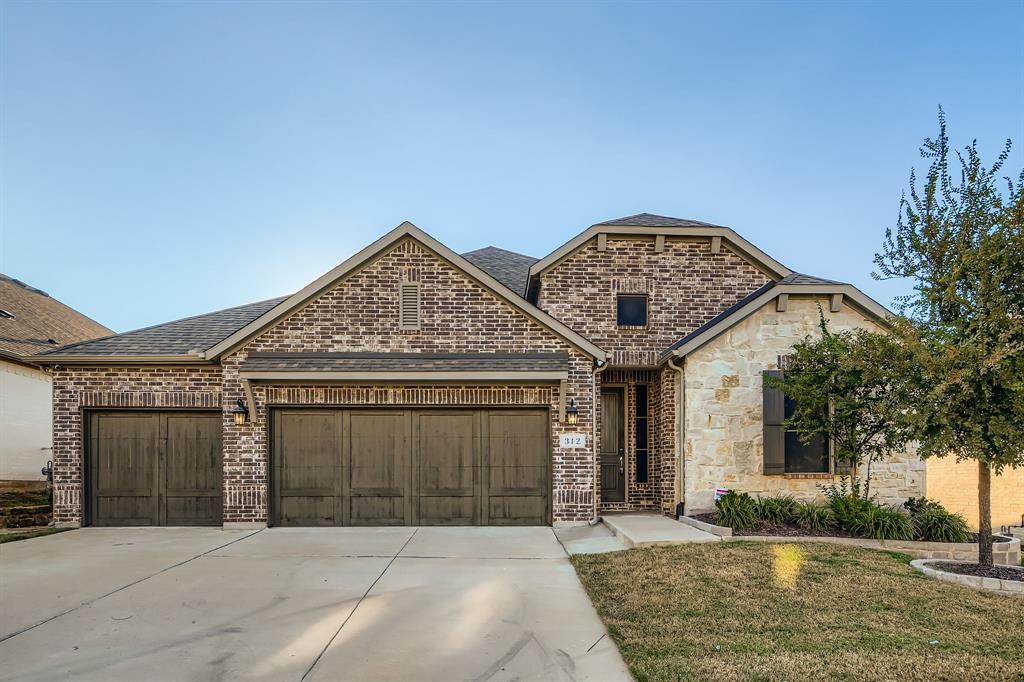 312 Magnolia Drive Oak Point, TX 75068 - Photo 1 of 28 French country inspired facade with brick siding, concrete driveway, a garage, and roof with shingles