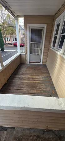 a view of an empty room with wooden floor and windows