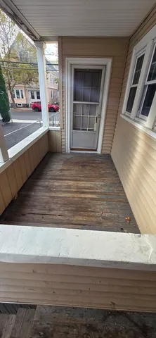 a view of an empty room with wooden floor and windows