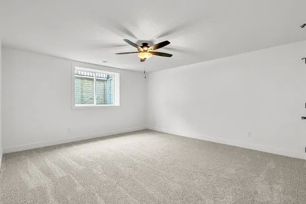 an empty room with windows and chandelier fan