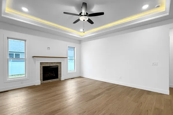 a view of an empty room with wooden floor fireplace and a window