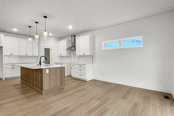 a large white kitchen with wooden floor