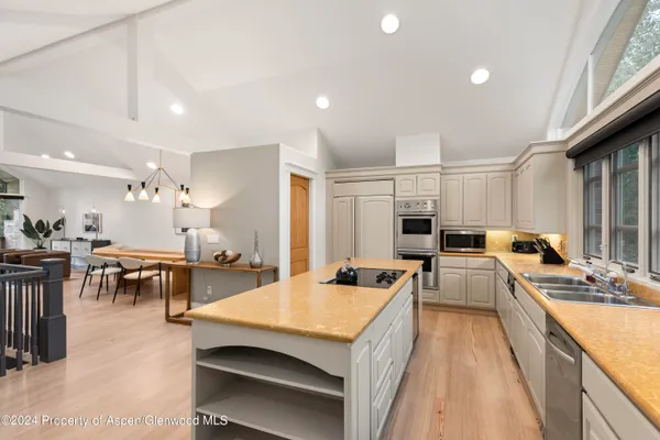 a large kitchen with kitchen island a large counter space a sink a stove and furniture