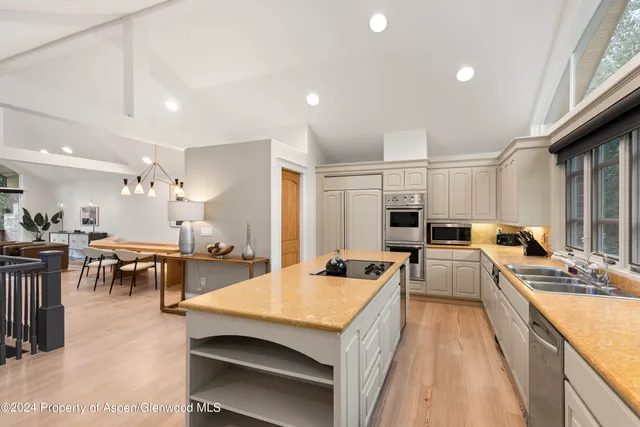 a large kitchen with kitchen island a large counter space a sink a stove and furniture