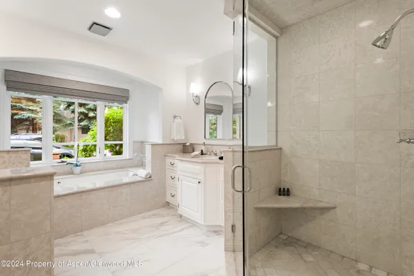 a large bathroom with a tub sink and mirror