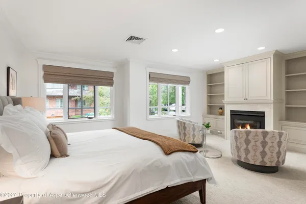 a large white bed sitting in a spacious bedroom next to a window