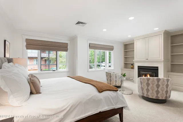 a large white bed sitting in a spacious bedroom next to a window