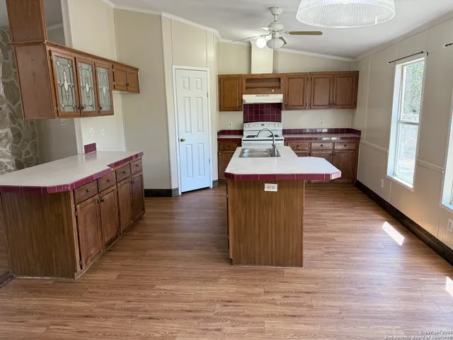 a kitchen with stainless steel appliances kitchen island a wooden floor and a sink