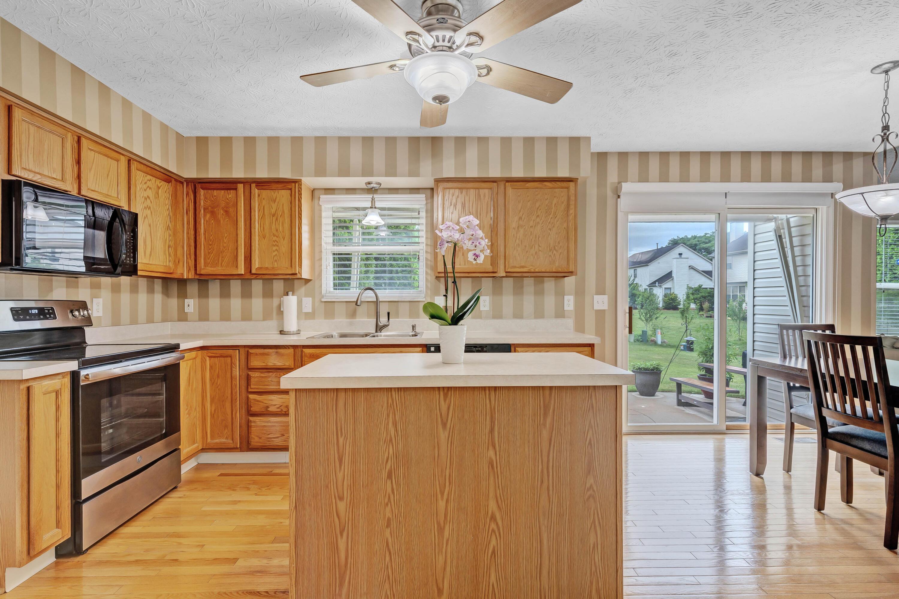 2136 Reeves Avenue Lewis Center, OH 43035 - Photo 12 of 57 • Hardwood flooring • Striped, painted walls • New General Electric® refrigerator ~ 2018 • New General Electric® range ~ 2018 • Kenmore® microwave • Kenmore® dishwasher • Oak cabinets • Center island • Double bowl, stainless steel sinktop with sprayer • Disposal • Pantry closet • 2 blinds