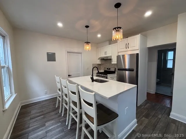 a kitchen with stainless steel appliances a dining table chairs refrigerator and cabinets