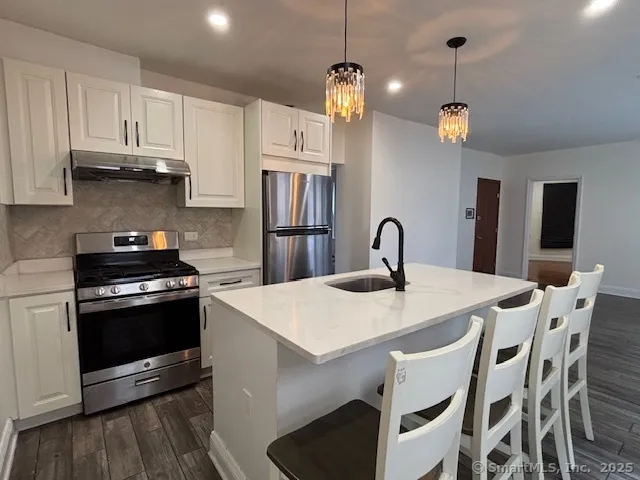 a kitchen with stainless steel appliances granite countertop a stove a refrigerator a kitchen island a sink and a refrigerator