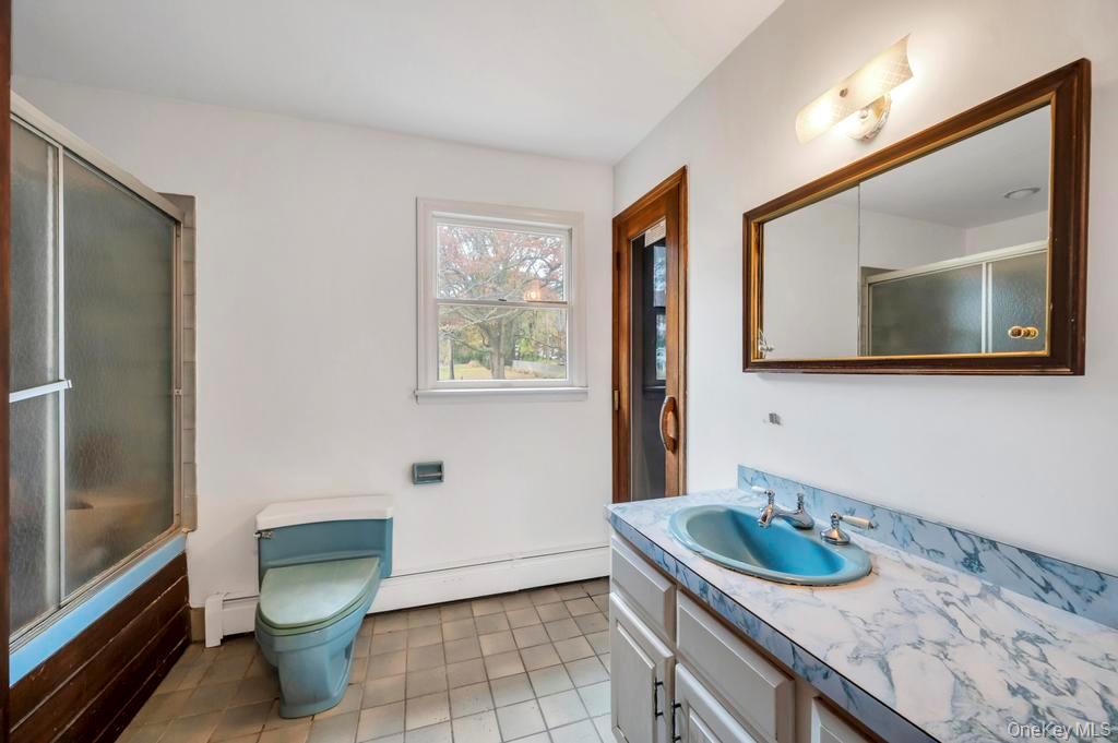 39 Bevin Road Northport, NY 11768 - Photo 32 of 44 Full bathroom with vanity, light tile patterned floors, baseboard heating, and bath / shower combo with glass door
