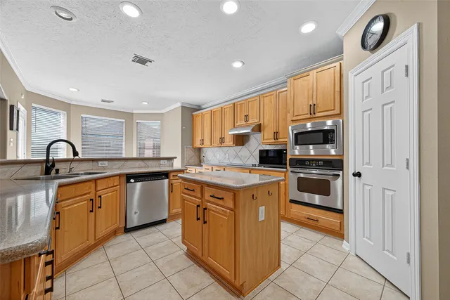 a kitchen with stainless steel appliances granite countertop a stove a sink and a refrigerator